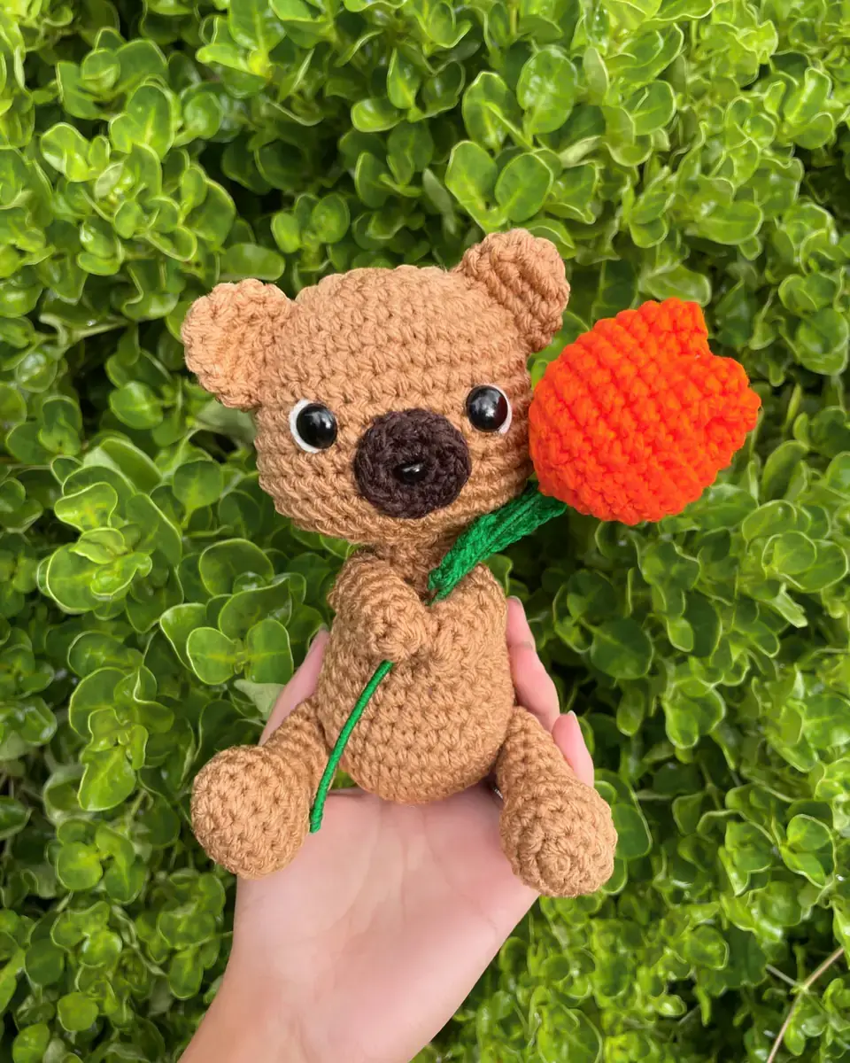 Osito café tejido sosteniendo un tulipán naranjo