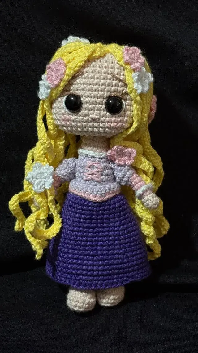 Muñeca amigurumi de pelo amarillo largo con flores y vestido morado