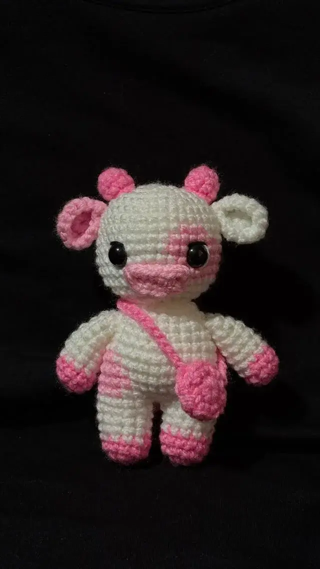 Vaquita amigurumi blanca con manchas rosadas y bolsito